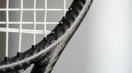 Détail macro d'une raquette de tennis mettant en évidence la biomécanique et l'équilibre du matériel