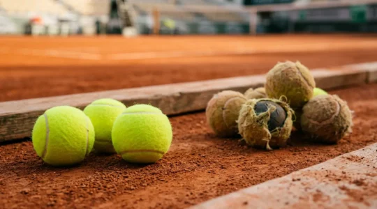 Gros plan sur des balles de tennis neuves et usées illustrant l'impact de la qualité sur la santé des joueurs