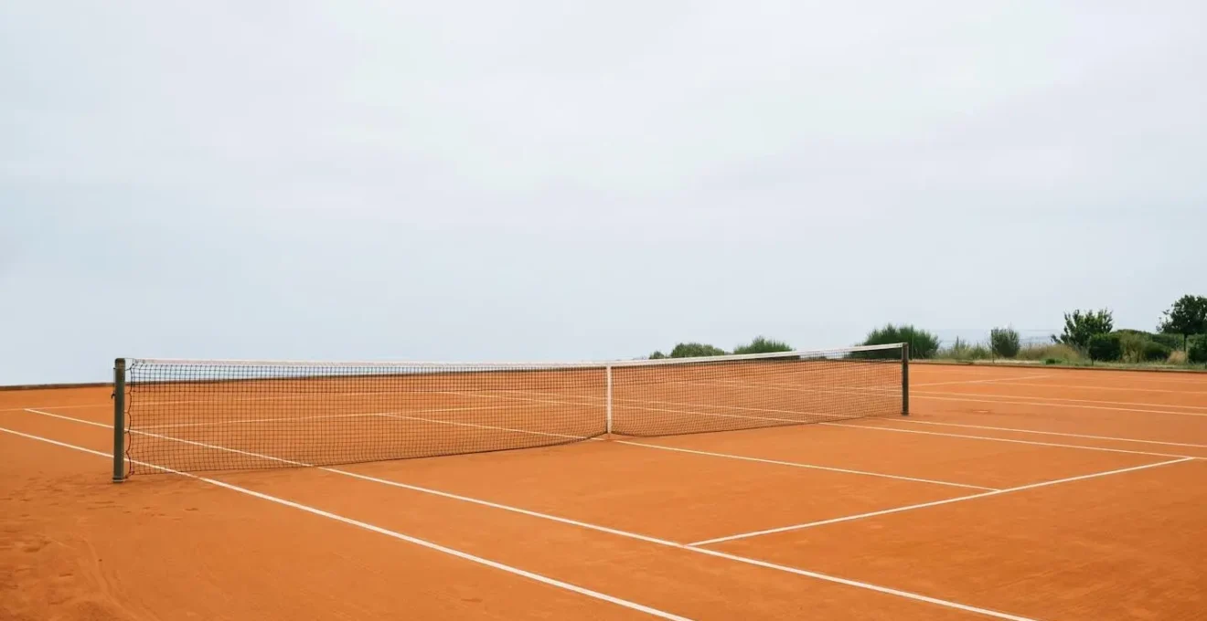 Vue latérale d'un court de terre battue français montrant une balle en trajectoire parabolique bombée au-dessus du filet
